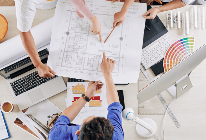 An architect discussing the plans made for a commercial building with his colleagues. 